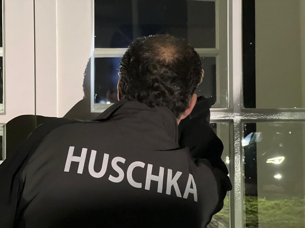 Huschka surveillant schijnt met zaklamp gebouw in.